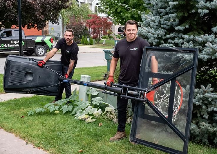 Two men transporting a large black trash can, representing bulk junk removal service in Chicago, IL.