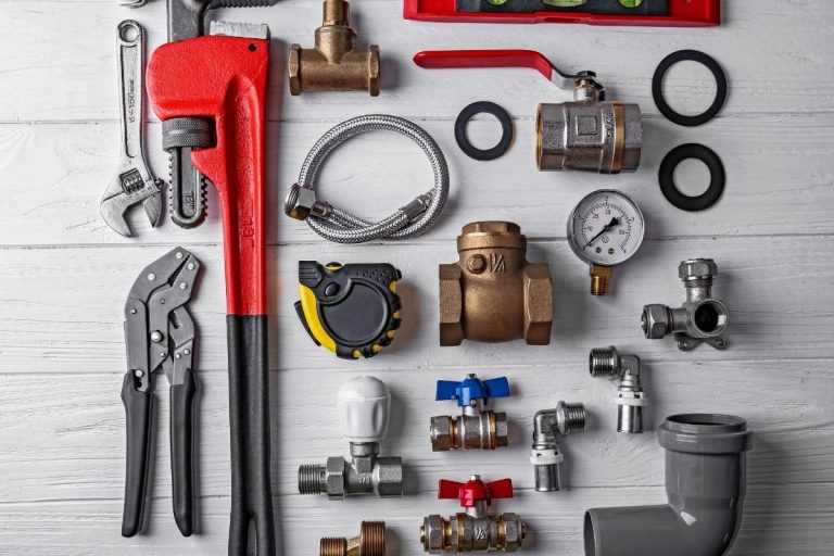 Various plumbing tools and accessories displayed on a clean white table, showcasing their different shapes and sizes.